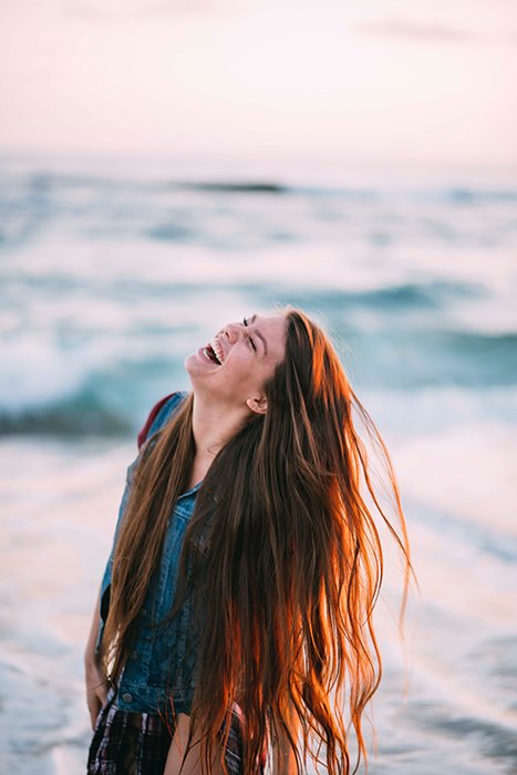 Fun portrait of a laughing female model tossing her auburn hair - how to smile for pictures