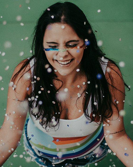 Fun portrait of a laughing female model covered in falling glitter - how to smile for pictures