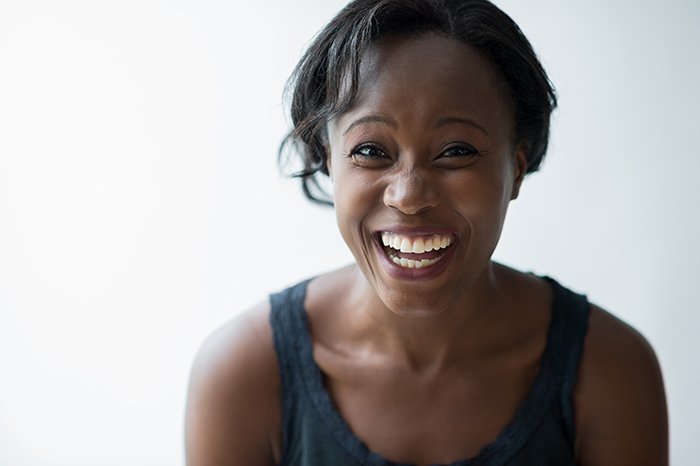 A woman laughing against a white background - smile for the camera tips