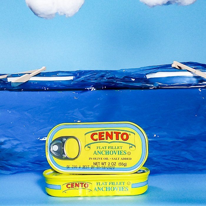smartphone product photography shot of cans of anchovies on painted background 