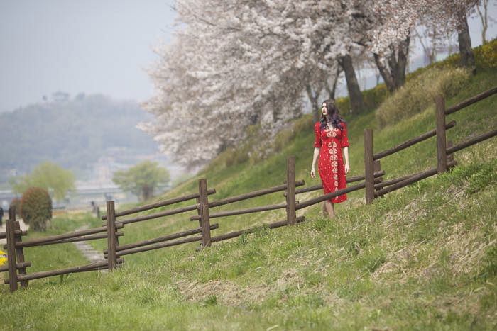 A female model in red dress walking through country fields - rule of space photography 