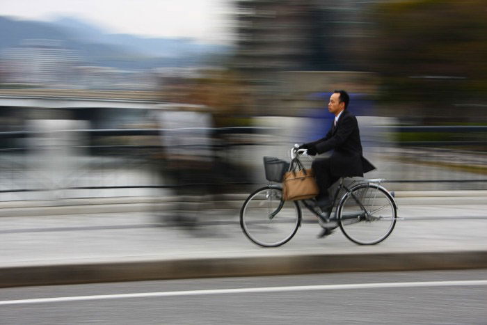 A man riding a bicycle in a cityscape with motio0n blurred background - rule of space photography 