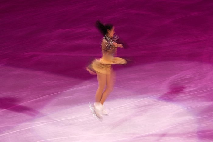 Blurry figure skating photography of a female skater twirling on the ice