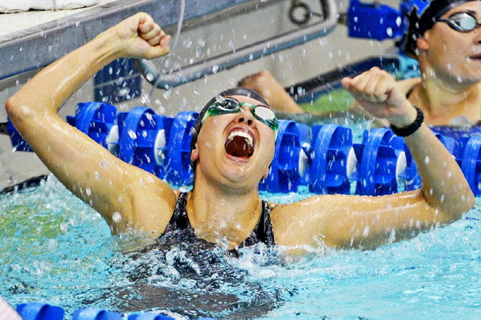 An action shot of a female swimmer celebrating victory after a race - how to take swimming pictures