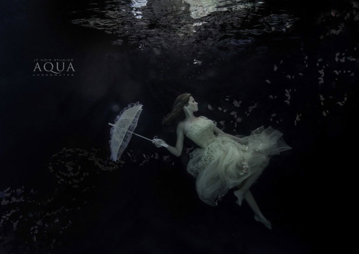 Atmospheric underwater photoshoot of a female model holding an umbrella underwater