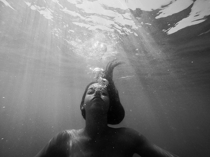 Atmospheric monotone underwater photo of a female swimmer 