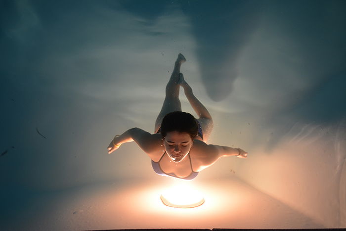 a stunning underwater portrait of a female swimmer posing over a warm light