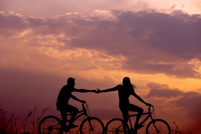 A silhouette of a couple on bikes at sunset in summertime