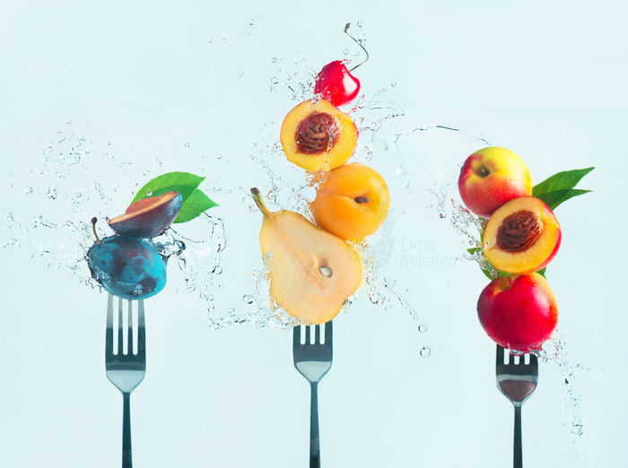 Cool still life featuring fruit on forks surrounded by water splashes