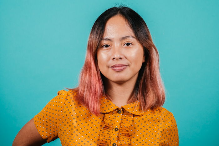 A portrait of a young woman take with a three-light studio setup against a teal backdrop