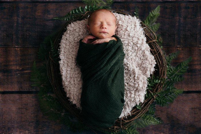 一个可爱的头顶肖像，一个小女孩在一个乡村的篮子里- diy新生儿摄影