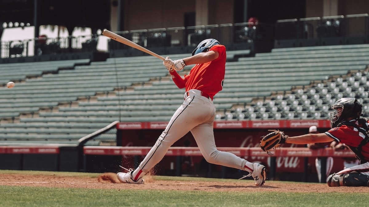 A batter hitting a ball with a catcher and empty stands behind as an example for baseball photography
