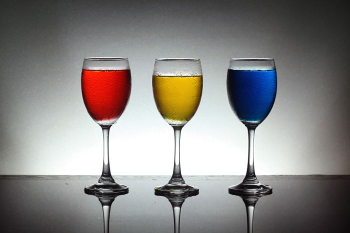 A product shot of three wine glasses with red, yellow and blue liquid inside - best camera flash