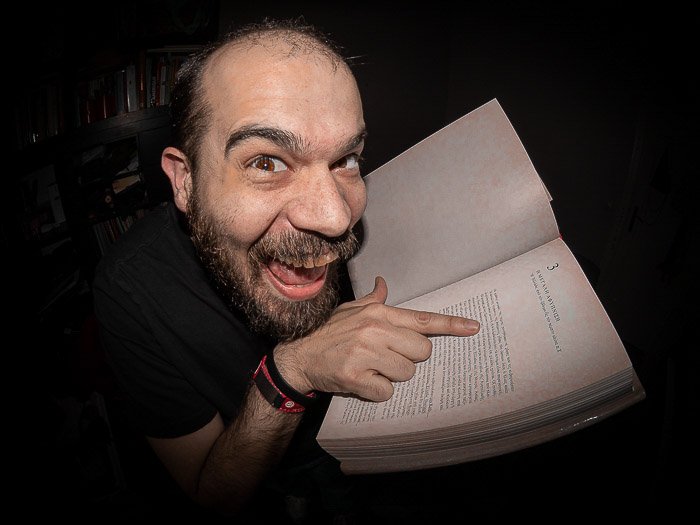 Humorous portrait of a man pointing to a book shot with a fisheye lens