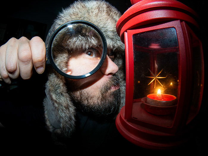 Humorous portrait of a man with a magnifying glass shot with a fisheye lens