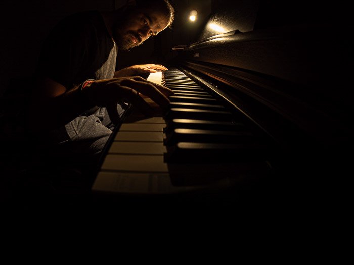 Atmospheric fisheye photo of a man playing piano in low light