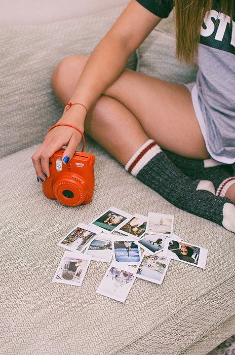 A girl with an instant camera looking over polaroid photos