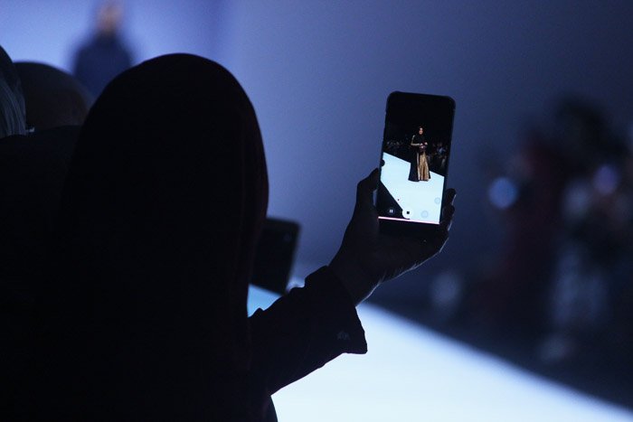 The silhouette of a person shooting smartphone fashion show photography
