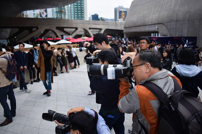 A group of photographers shooting a fashion portrait of a female model outdoors