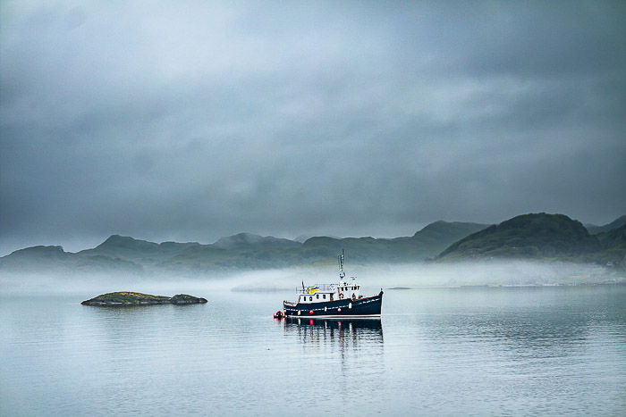 A boat in foggy seascape at sunset