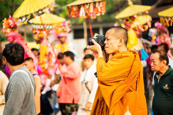 A buddhist monk taking photos with a DSLR outdoors among crowds - how to start a camera club