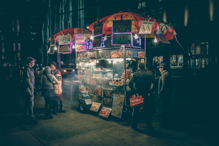 Street portrait of people at an outdoor food stall at night - photography themes