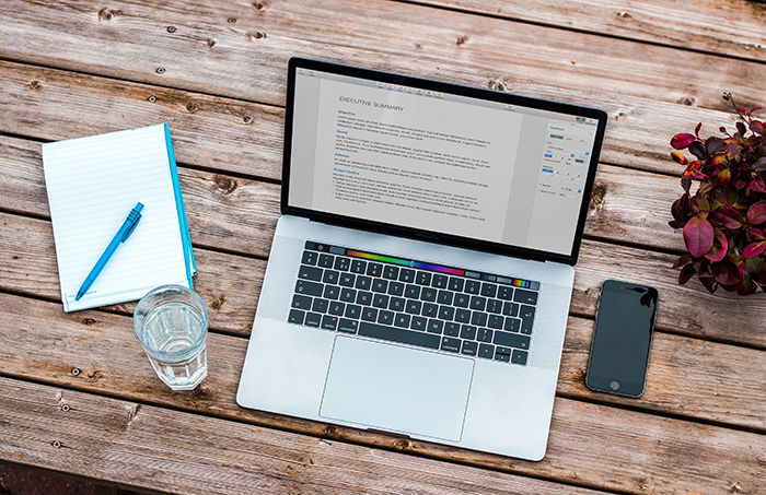 A laptop, phone and notebook on a wooden table 