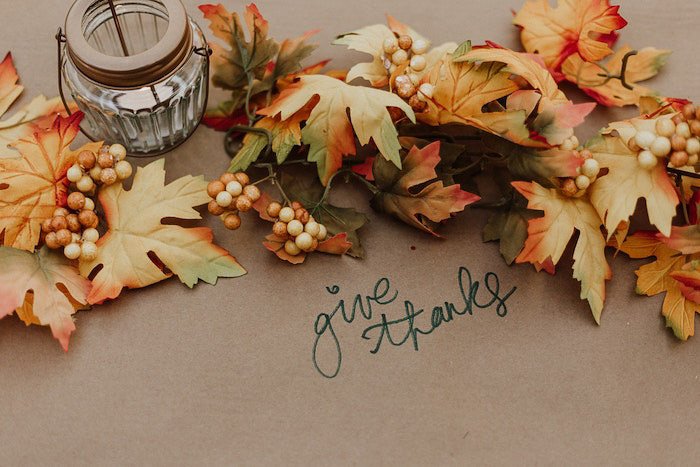 A thanksgiving photography flatlay featuring autumn leaves and a candle