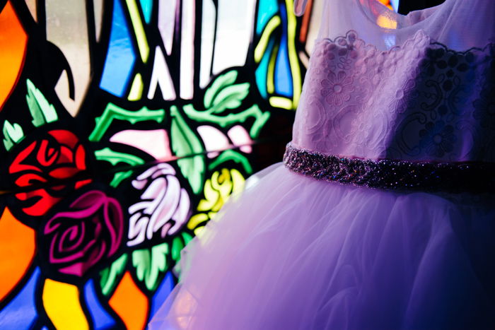 Wedding portrait of a purple bridesmaids dress in front of stained glass - wedding photography business tips