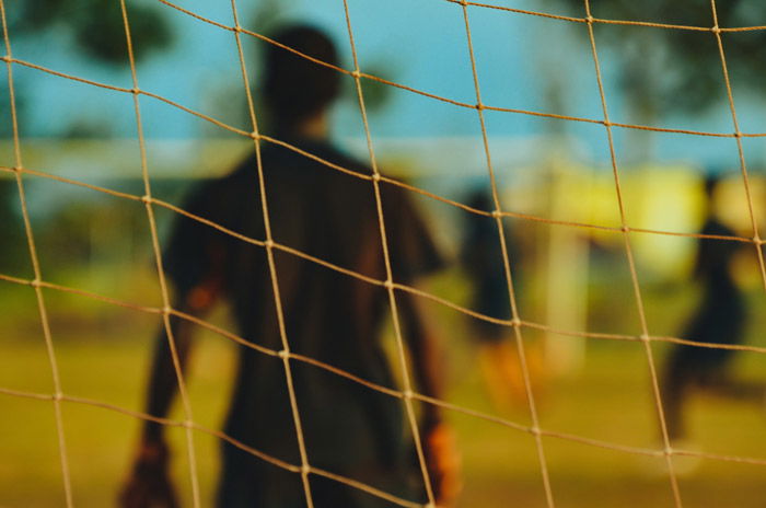 Artistic soccer photography shot of a player shot through the net