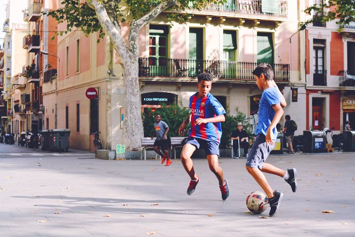 A soccer photo of two boys playing football on the street 