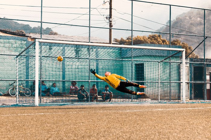 A soccer photography shot of a goalkeeper trying to save a goal