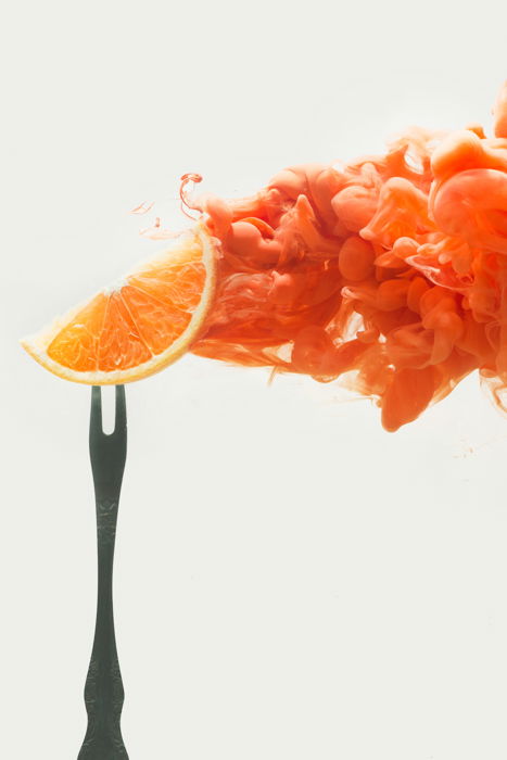 an orange slice on a fork - setup to shoot colorful paint in water photography