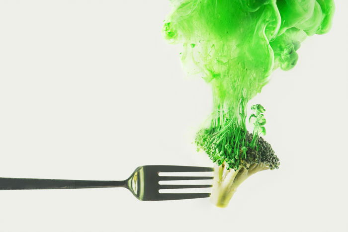 A fork of broccoli with green cloud shot using colorful paint in water technique