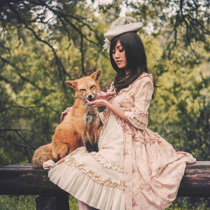 A vintage style portrait of a female model in old style costume holding a fox 