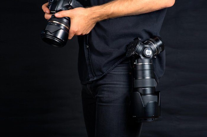 A photographer holding a DSLR wearing a Trilens Lens Holster