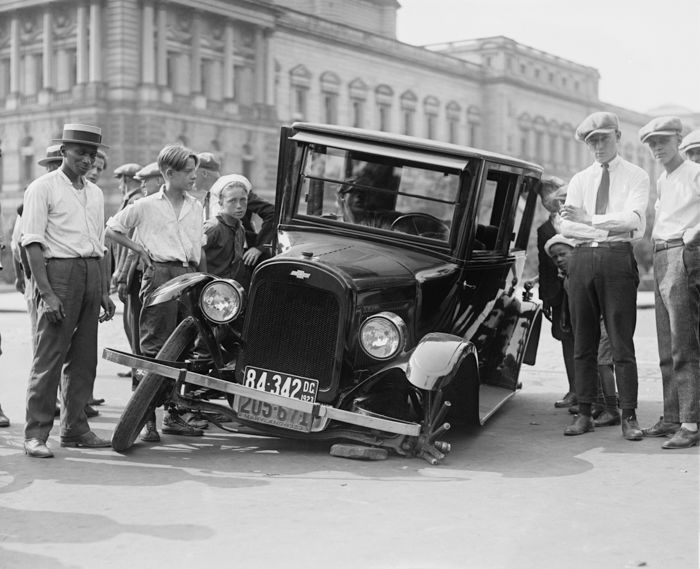 black and white vintage photography of a group of men and boys standing around a broken down vintage car