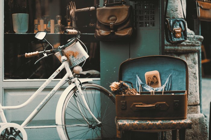 an outdoor still life of antiques such as a bicycle, leather bags and photos - vintage photography tips