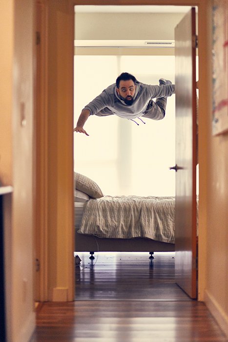 A funny photography portrait of a man levitating over his bed