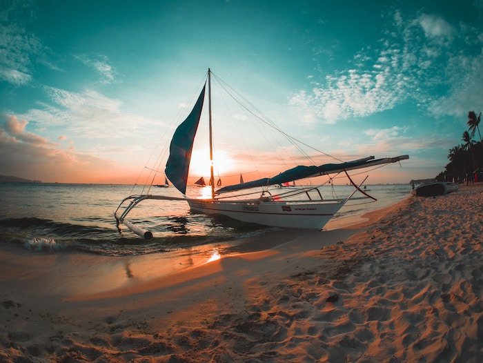 a beautiful sunset shot of a boat on a beach using the teal and orange color scheme