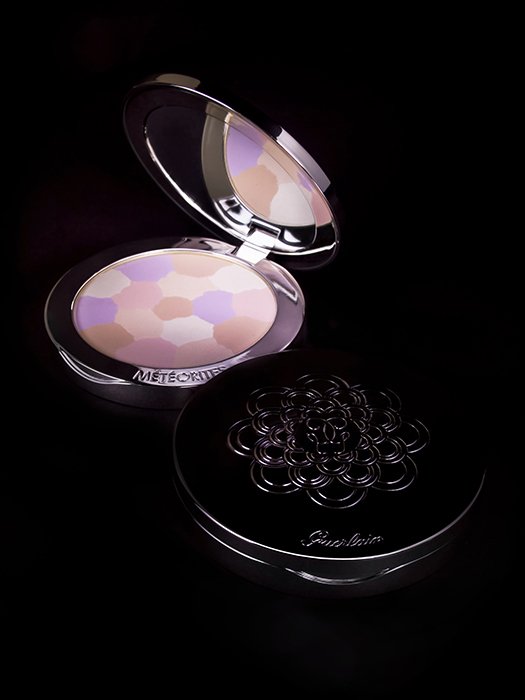 A makeup product shot of compact powder against black background