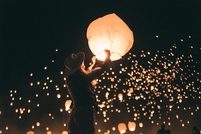 Dreamy night portrait of a girl lighting a sky lantern 