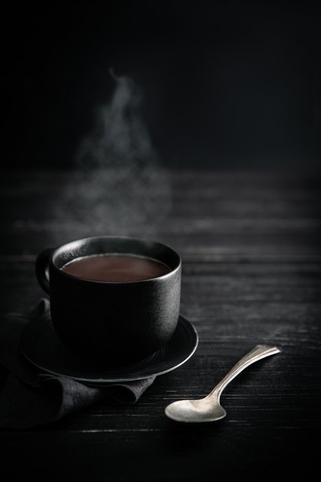 Stylish drink photo of a cup of steaming coffee against a dark background