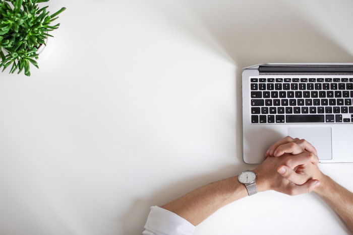 An overhead shot of a man writing a photo licensing agreement on a laptop at a desk