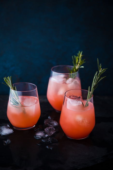 Stylish drink photo of three orange cocktails against a dark background