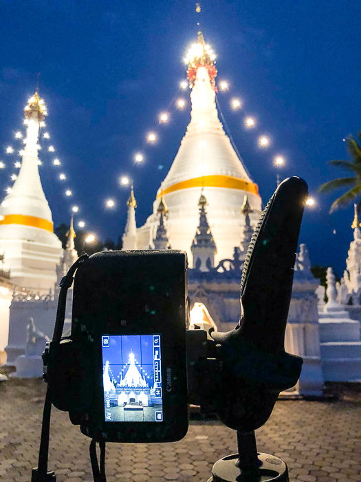 a dslr on a tripod shooting starburst photography over a building at night