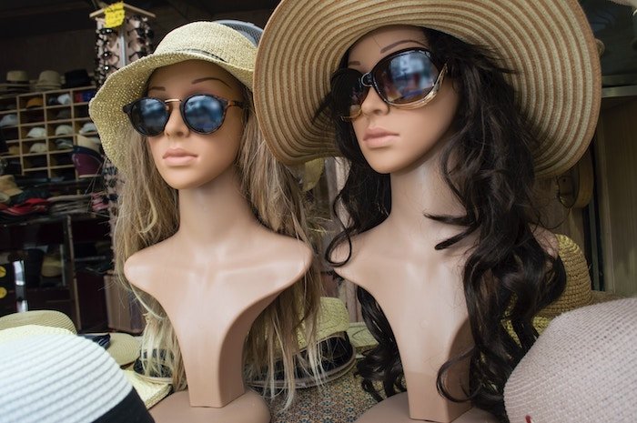 Two mannequin busts with sunglasses and sun hats on