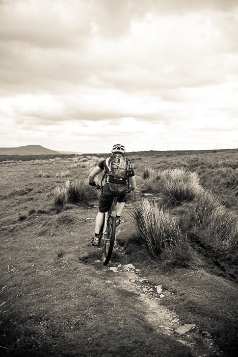 monochrome shot of a cyclist moving through a landscape - adventure photography skills