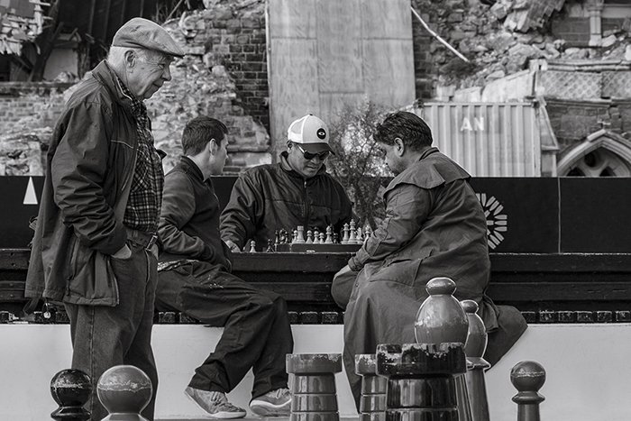 candid street photo of people playing chess outdoors