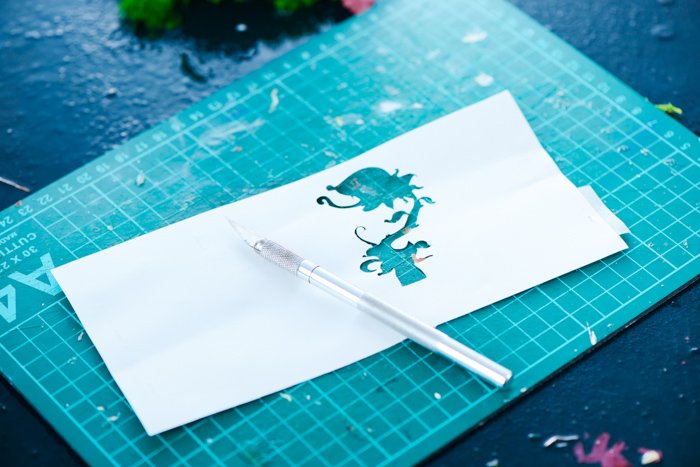 a cut out silhouette of a flower in a piece of paper on a cutting mat